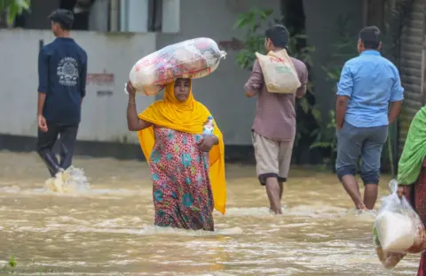  EPA-EFE/REX/Shutterstock People wade through floodwater at a flood-affected area in Burichong, Comilla district, Bangladesh