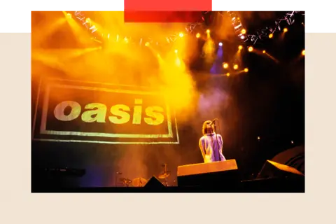 Getty Images Liam Gallagher in a white coat singing in front of the Oasis logo