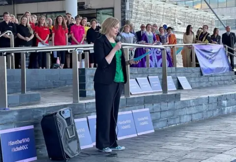 Elizabeth Atherton Elizabeth Atherton stands on the Senedd steps making a speech