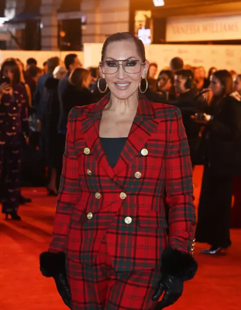 Gareth Cattermole/Getty Images Michelle Visage in red suit on red carpet at The Dominion Theatre