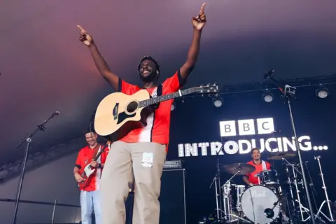 Kian Boyle / BBC Myles Smith holds his arms above his head and conducts the audience as he performs at Radio 1's Big Weekend in Luton, May 2024